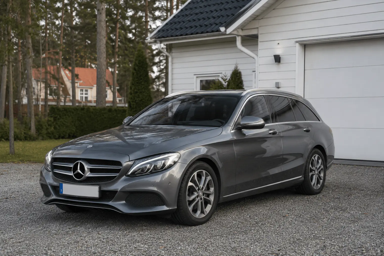 Mercedes C-klass kombi W205 i grå metallic parkerad utanför ett villagarage - vanlig syn på den svenska begagnatmarknaden